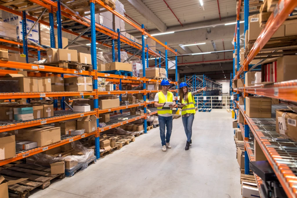 two warehouse workers walking distribution storage area discussing about logistics organization